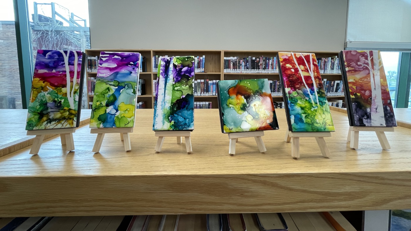 alcohol ink on tile art pieces displayed on a book shelf